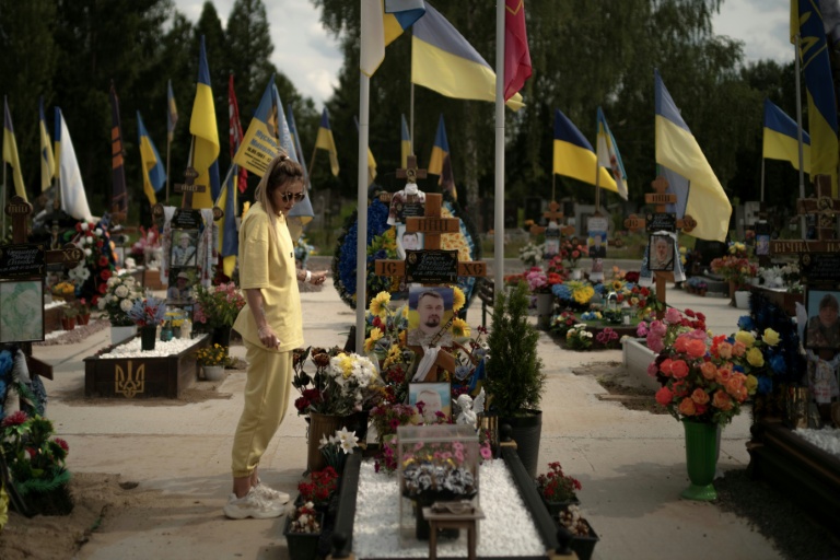 Une jeune femme se recueille devant la tombe d'un soldat au cimetière de Sumy, dans le nord-est de l'Ukraine le 11 juin 2025