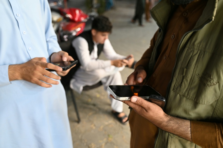 Des Afghans consultent leurs téléphones portables, le 1er octobre 2025 à Kaboul