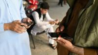 Des Afghans consultent leurs téléphones portables, le 1er octobre 2025 à Kaboul
