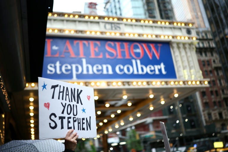 Une personne brandit une pancarte en soutien à l'animateur Stephen Colbert, devant le théâtre où il s'apprête à enregistrer le dernier épisode de son 