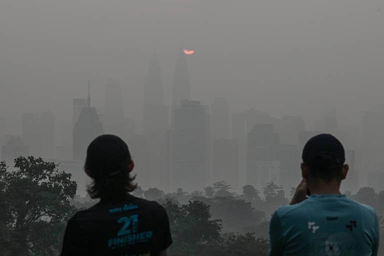 Deux personnes se tiennent devant la capitale malaisienne saturée de fumées toxiques, à Kuala Lumpur, le 17 octobre 2026