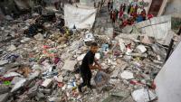 Un garçon palestinien ramasse des objets le 30 mai 2024 au milieu des décombres d'un bâtiment détruit par une frappe israélienne nocturne à Nousseirat, dans le centre de la bande de Gaza, où une guerre oppose Israël au mouvement islamiste palestinien Hamas