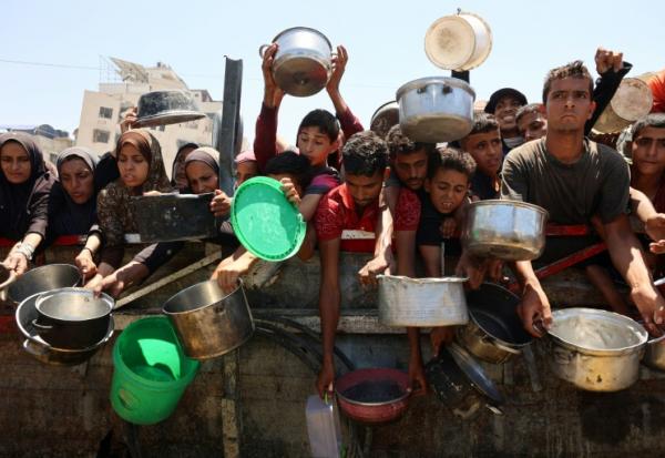 Des Palestiniens affamés attendent de recevoir une ration de soupe de lentilles lors d'une distribution alimentaire à Gaza, le 2 août 2025