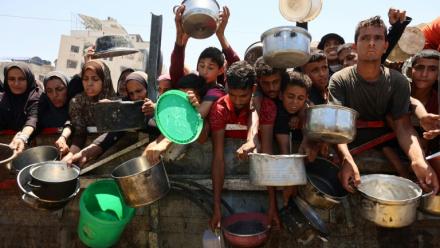 Des Palestiniens affamés attendent de recevoir une ration de soupe de lentilles lors d'une distribution alimentaire à Gaza, le 2 août 2025