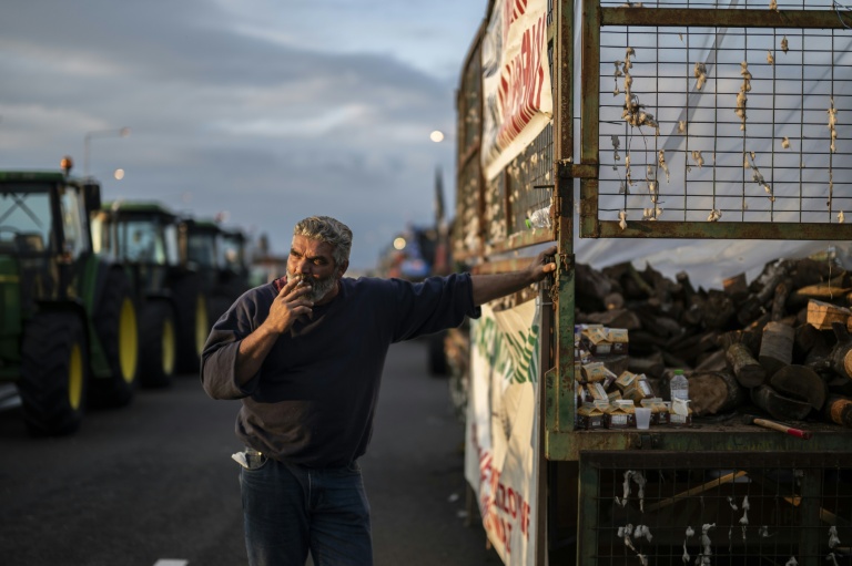 Un agriculteur attend parmi les tracteurs qui bloquent en signe de protestation une autoroute près de la ville de Karditsa, dans le centre de la Grèce, le 8 décembre 2025
