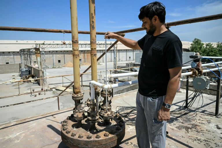 Un ouvrier mesure le niveau de gaz dans un réservoir de stockage presque vide d'une usine de fabrication de carreaux de céramique, fermée en raison des contraintes d'approvisionnement en propane, le 25 mars 2026 à Morbi, en Inde