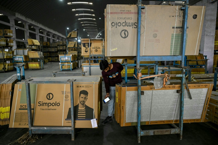 Un ouvrier scanne des carreaux de céramique emballés avant leur livraison dans une usine confrontée à des difficultés d'approvisionnement en gaz, le 26 mars 2026 à Morbi, en Inde