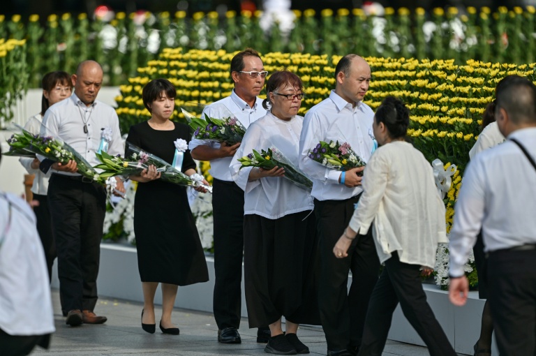 Des invités attentent de pouvoir déposer un bouquet de fleurs au niveau du cénotaphe commémorant le bombardement atomique de 1945, le 6 août 2025 à Hiroshima au Japon