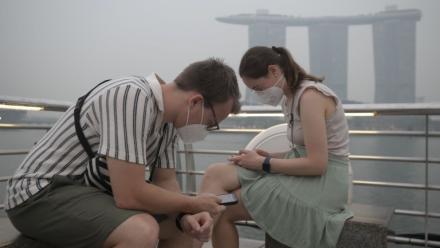 Des touristes portent des masques de protection contre les fumées générées par les incendies indonésiens, le 15 octobre 2026 à Singapour