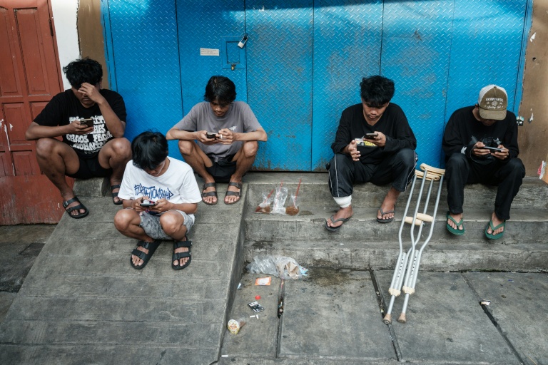 Des enfants utilisent leur smartphone à Jakarta le 26 mars 2026.