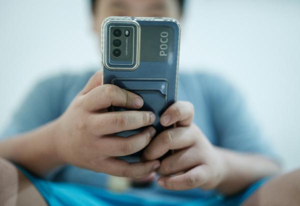 Bradley Rowen Liu, 11 ans, regarde une vidéo sur son téléphone le 25 mars 2026 à Jakarta, en Indonésie