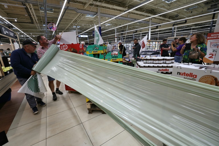 Des membres des syndicats agricoles FDSEA 72 et Jeunes Agriculteurs (JA) enveloppent des produits des produits contenant de l'acétamipride, un pesticide néonicotinoïde, retirés des rayons lors d'une opération de protestation dans un supermarché de Mundolsheim, le 20 août 2025 dans le Bas-Rhin