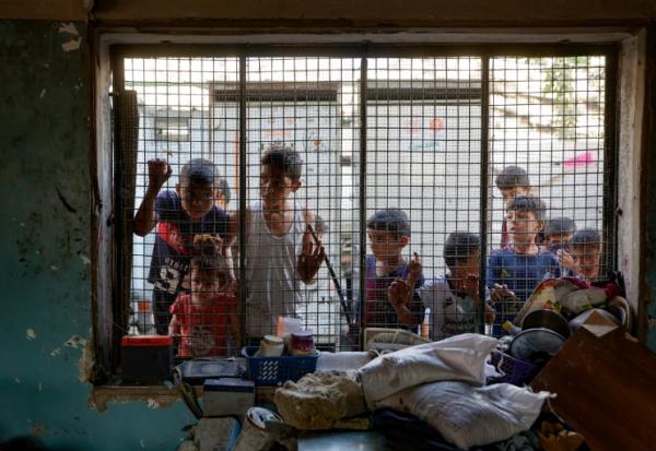 Des enfants palestiniens regardent depuis le grillage d'une salle de classe endommagée de l'école al-Farabi transformée en abri pour déplacés, après avoir été touchée par une frappe israélienne dans la ville de Gaza, le 7 septembre 2025