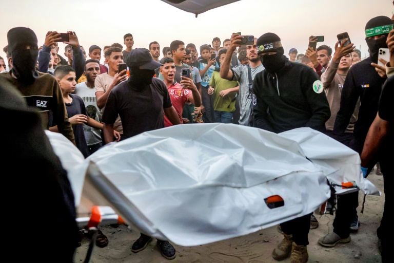 Des Palestiniens regardent des combattants du Hamas transporter un corps retrouvé dans un tunnel vers une ambulance dans une zone située au nord de Khan Younès, dans le sud de la bande de Gaza, le 28 octobre 2025