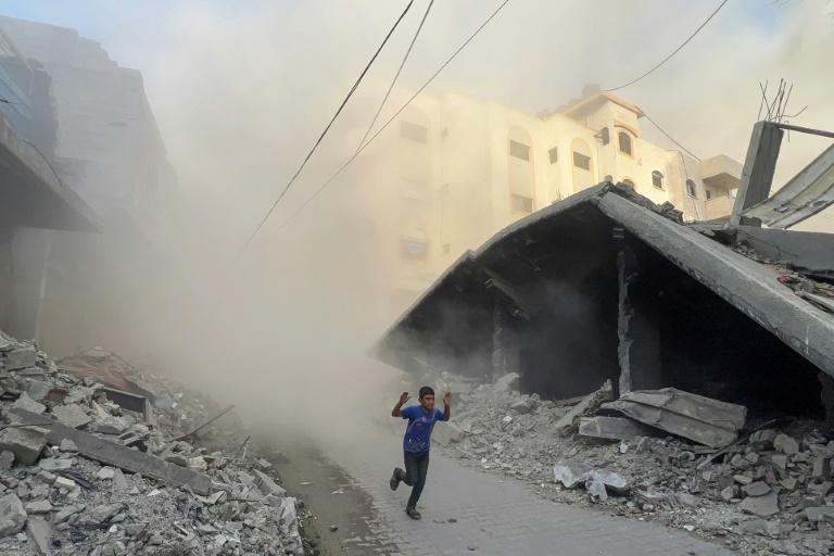 Un garçon palestinien fuit en courant des frappes aériennes à Jabalia, dans le nord de la bande de Gaza, le 19 août 2025

