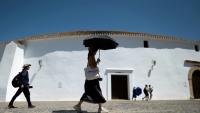 Une femme portant des gants et un chapeau s'abrite du soleil avec un parapluie à Ronda, dans le sud de l'Espagne, le 2 juillet 2025 