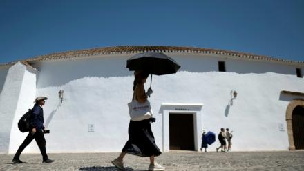 Une femme portant des gants et un chapeau s'abrite du soleil avec un parapluie à Ronda, dans le sud de l'Espagne, le 2 juillet 2025 