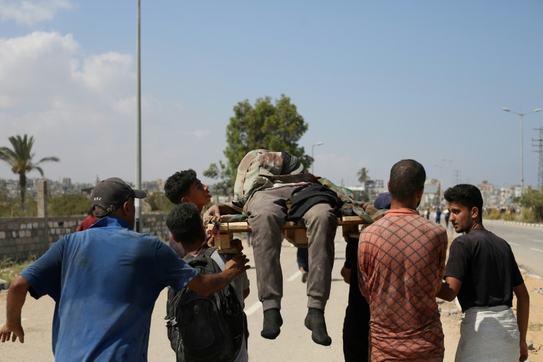 Des Palestiniens portent une personne tuée alors qu'elle venait chercher de l'aide dans un site de la Fondation humanitaire de Gaza (GHF), une organisation soutenue par Israël et les Etats-Unis, dans le centre de la bande de Gaza, le 2 août 2025