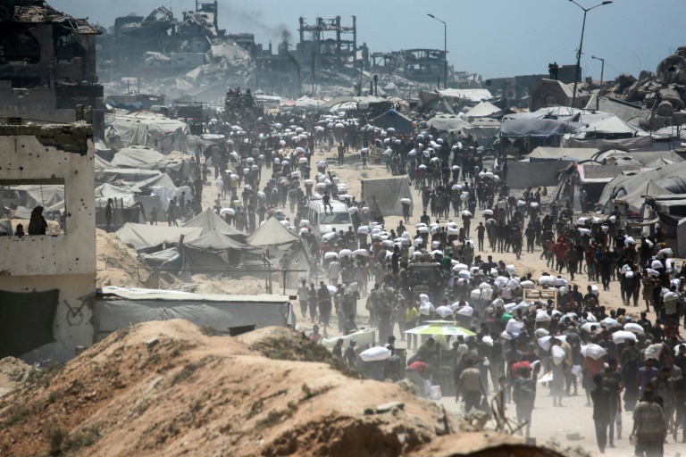 Des Palestiniens portent des sacs de farine à Jabalia, dans le nord de la bande de Gaza, le 1er août 2025
