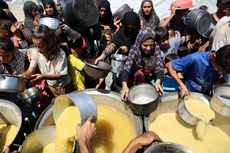 Des Palestiniens reçoivent de la soupe aux lentilles à un point de distribution de nourriture dans la ville de Gaza, le 1er août 2025