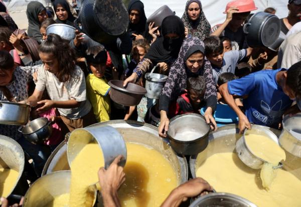 Des Palestiniens reçoivent de la soupe aux lentilles à un point de distribution de nourriture dans la ville de Gaza, le 1er août 2025