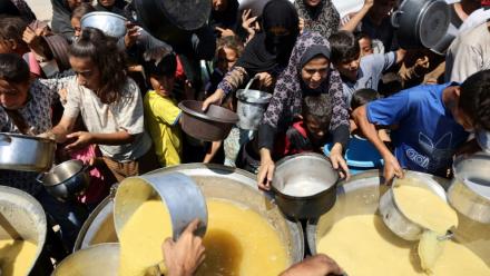 Des Palestiniens reçoivent de la soupe aux lentilles à un point de distribution de nourriture dans la ville de Gaza, le 1er août 2025