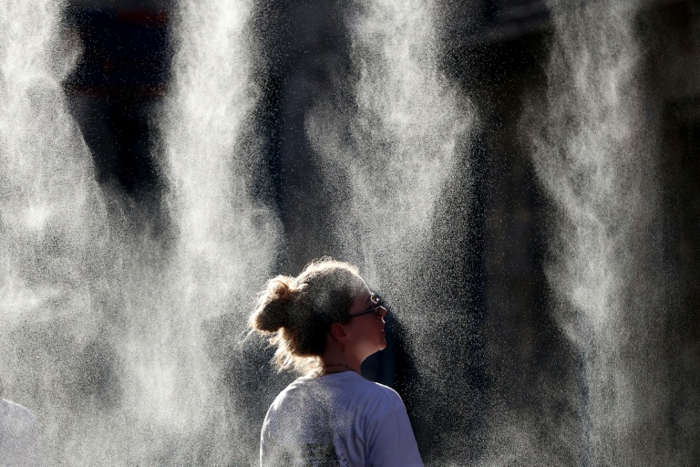 Une femme se rafraîchit sous un brumisateur pendant la fête de la musique, lors d'un épisode de canicule à Bordeaux, dans le sud-ouest de la France, le 21 juin 2026
