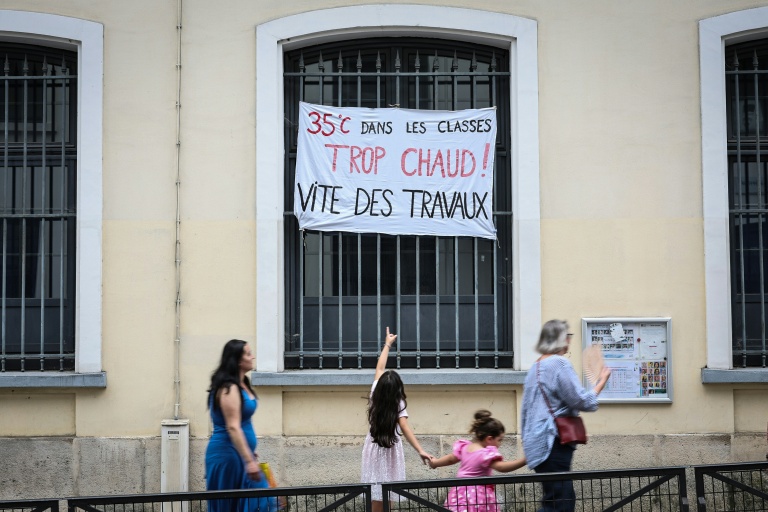 Une enfant pointe du doigt une banderole dénonçant les températures extrêmes en classe, devant une école à Paris, le 18 juin 2026
