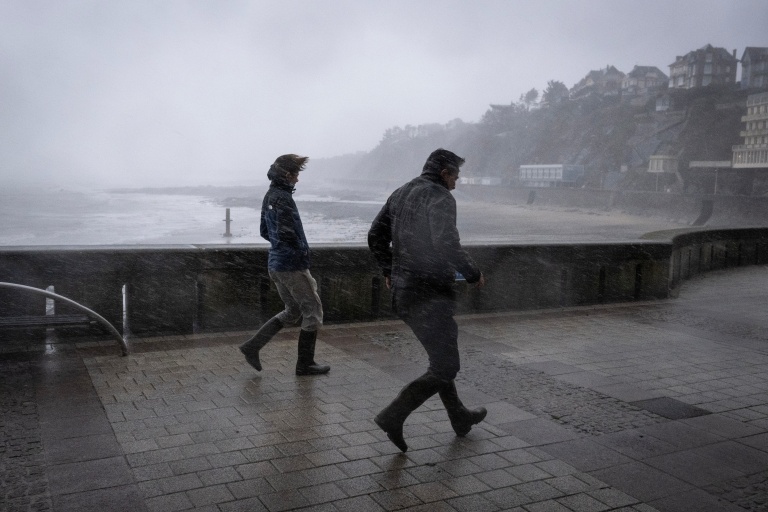 Des promeneurs pris dans les bourrasques de la tempête Austen sur le front de mer à Granville, dans la Manche, le 23 octobre 2026