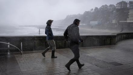 Des promeneurs pris dans les bourrasques de la tempête Austen sur le front de mer à Granville, dans la Manche, le 23 octobre 2026