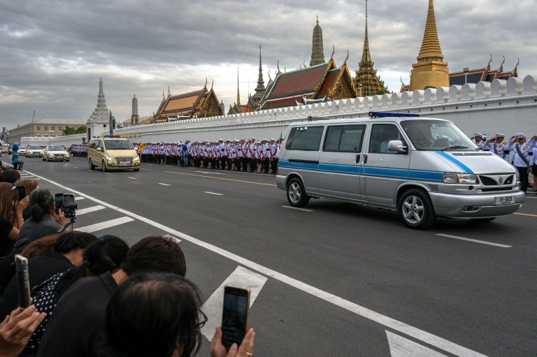 Des Thaïlandais assistent au passage du cortège funèbre amenant la dépouille de la reine mère Sirikit au Palais royal de Bankok, le 26 octobre 2025