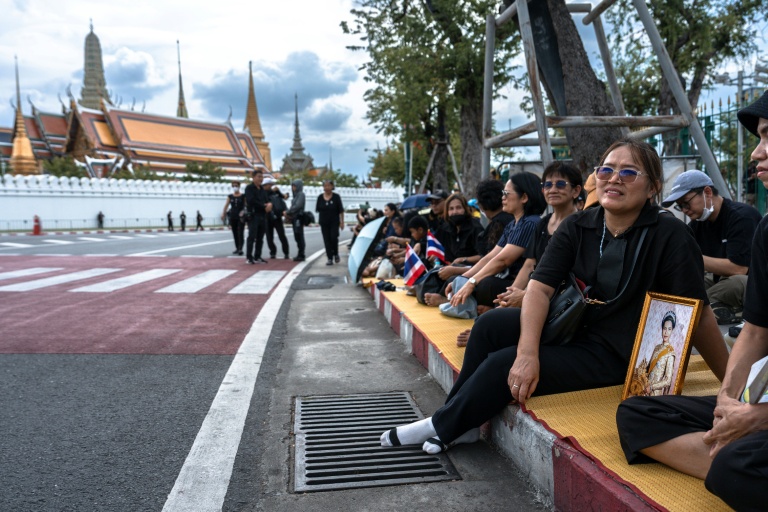 Des Thaïlandais en deuil attendent le passage du cortège funéraire après le décès de la reine mère Sirikit, le 26 octobre 2025 à Bangkok