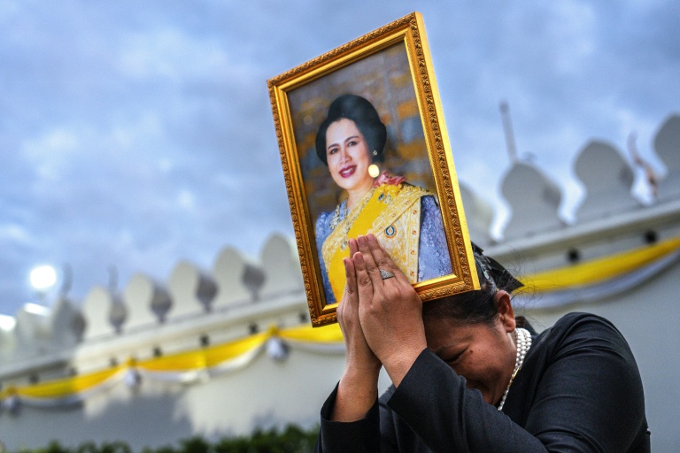 Une femme endeuillée tient un portrait de la reine mère Sirikit de Thaïlande au passage du cortège funéraire, le 26 octobre 2025 à Bangkok