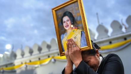 Une femme endeuillée tient un portrait de la reine mère Sirikit de Thaïlande au passage du cortège funéraire, le 26 octobre 2025 à Bangkok