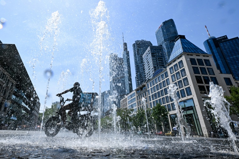 Un cycliste se rafraîchit entre les jeuts d'eau d'une fontaine à Francfort, le 26 juin 2026 en Allemagne, lors d'un épisode de canicule en Europe