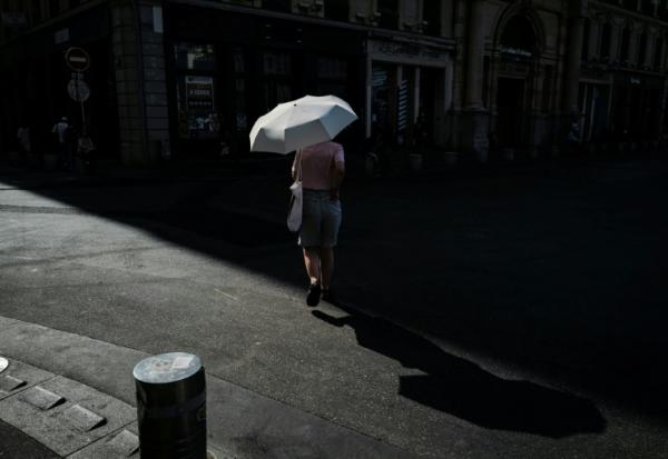 Une femme marche sous un parapluie pour se protéger du soleil lors d'une vague de chaleur à Lyon, dans le Rhône, le 24 juin 2026