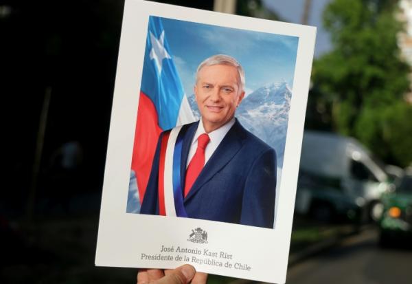 Une personne brandit une pancarte José Antonio Kast, sur laquelle figurent son nom et "Président de la République du Chili", à Santiago, le 14 décembre 2025