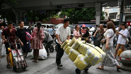 Un homme transportant des ballots de vêtements vers un marché de gros de Canton, en Chine, le 16 avril 2026