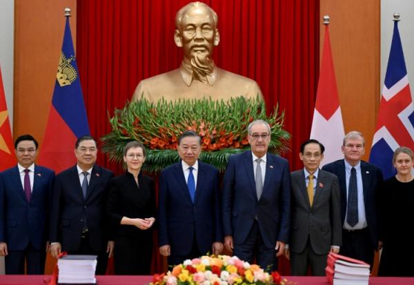 Le président du Vietnam, To Lam (c), la Première ministre du Liechtenstein, Brigitte Haas (3e g), et le président de la Suisse, Guy Parmelin (3e d), aux côtés de délégués lors de la cérémonie de signature de l'accord de libre-échange entre le Vietnam et l'AELE, le 18 octobre 2026 à Hanoï