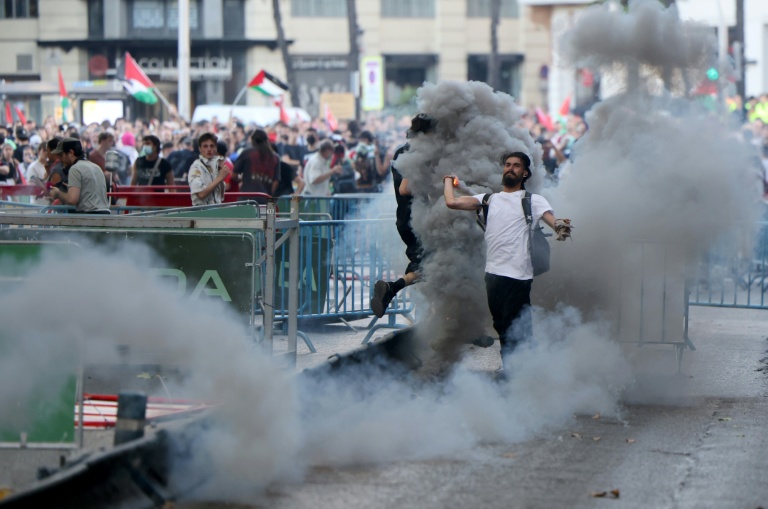 Un homme renvoie une grenade lacrymogène vers la police, après l'invasion des rues par des manifestants propalestiniens pendant la 21e et dernière étape du Tour d'Espagne cycliste, le 14 septembre 2025
