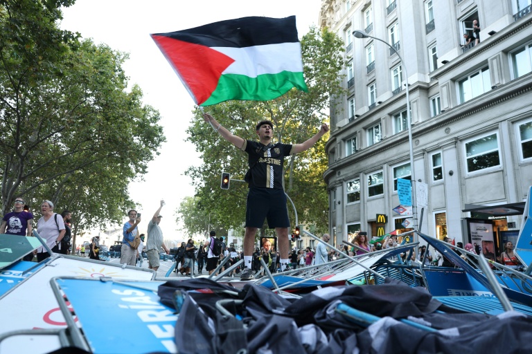 Un manifestant propalestinien brandit un drapeau palestinien alors que les manifestants ont envahi les rues pendant la 21e et dernière étape du Tour d'Espagne cycliste, le 14 septembre 2025 à Madrid