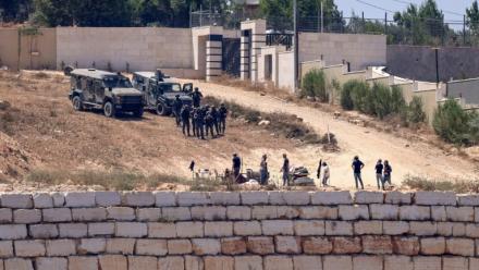 Des soldats israéliens (en haut) montent la garde aux côtés de colons devant des maisons palestiniennes dans le village de Qusra, au sud de Naplouse, en Cisjordanie occupée, le 12 août 2026