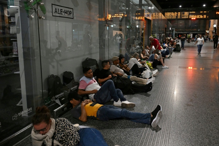 Des voyageurs sont assis ou allongés au sol alors qu'ils se préparent à passer la nuit dans la gare de Cordoue en raison d'une méga-panne électrique affectant l'Espagne et le Portugal le 28 avril 2025