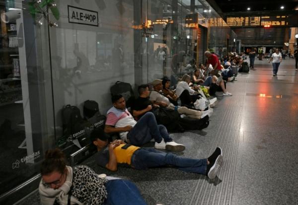 Des voyageurs sont assis ou allongés au sol alors qu'ils se préparent à passer la nuit dans la gare de Cordoue en raison d'une méga-panne électrique affectant l'Espagne et le Portugal le 28 avril 2025