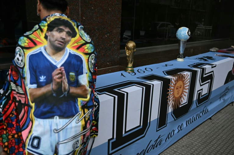 Un fan enveloppé dans une banderole à l'effigie de Diego Maradona, devant le tribunal de San Isidro, lors de la dernière audience consacrée aux plaidoiries de la défense dans le procès concernant son décès, le 21 octobre 2026 dans la province de Buenos Aires, en Argentine
