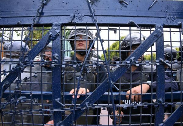 Des policiers montent la garde lors d'une manifestation de partisans de l'ancien Premier ministre népalais KP Sharma Oli protestant contre son arrestation, le 29 mars 2026 à Katmandou, au Népal