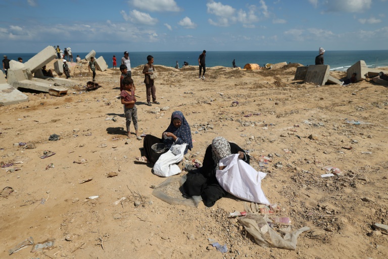 Des Palestiniennes fouillent le sol à la recherche de restes de colis de vivres à Nousseirat, dans le centre de la bande de Gaza, le 5 août 2025