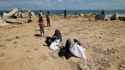Des Palestiniennes fouillent le sol à la recherche de restes de colis de vivres à Nousseirat, dans le centre de la bande de Gaza, le 5 août 2025
