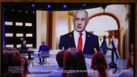 Cette photo prise sur un écran de TF1, montre le président français Emmanuel Macron, alors qu'une photo du Premier ministre israélien Benjamin Netanyahu s'affiche en arrière-plan, lors d'une émission dans les studios de télévision de Saint-Denis, le 13 mai 2025