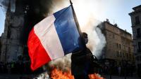 Un manifestant avec un drapeau français devant un feu, le 17 octobre 2026 à Marseille